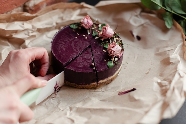 Una donna taglia una torta con un coltello. Taglia un pezzo di torta. Deliziosa torta naturale. Bellissimo dessert con decorazioni. Un dolce naturale.