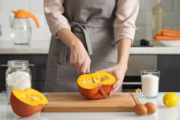 Una donna taglia una zucca per fare una torta nella sua cucina