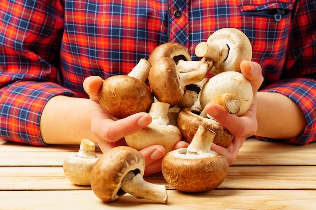 Una donna tiene i funghi champignon nelle sue mani. Il concetto di corretta alimentazione e salute