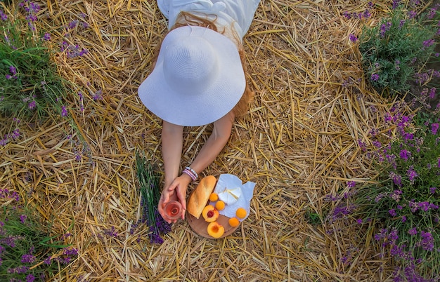 Una donna tiene il vino in bicchieri. Picnic nel campo di lavanda. Messa a fuoco selettiva.