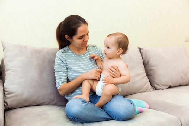 Una donna tiene in braccio un bambino e gli legge un libro. madre e figlio sul divano.