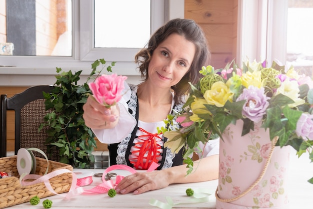 Una donna tiene in mano un fiore. Piante fatte di materiali artificiali realizzate da un fiorista per il design.