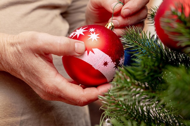 Una donna tiene in mano un giocattolo di Capodanno con una palla che decora l'albero di Natale
