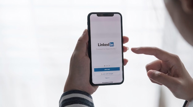 Una donna tiene in mano un iPhone con l'applicazione LinkedIn sullo schermo.LinkedIn è un'app per la condivisione di foto per smartphone.