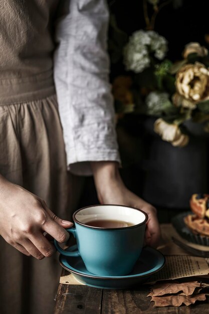 Una donna tiene in mano una tazza di tè blu e un piatto di croissant Rilassamento con caffè al latte