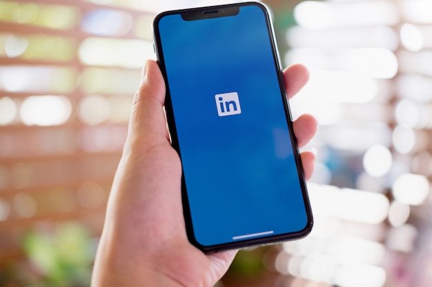 Una donna tiene Smartphone Xs con l'applicazione LinkedIn sullo schermo.LinkedIn è un'app di condivisione foto per smartphone.