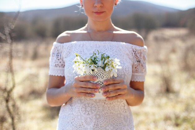 Una donna tiene un mazzo di fiori in un campo.