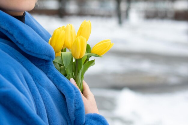 Una donna tiene un mazzo di tulipani gialli nella neve.