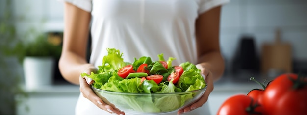Una donna tiene un piatto con l'insalata di cibo nelle mani sullo sfondo della cucina