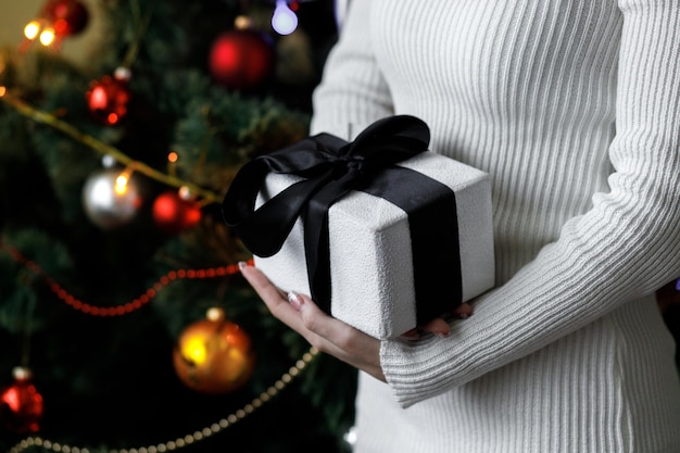 Una donna tiene un regalo Decorazioni di Capodanno Preparazione per le vacanze Regali di Capodanno sui ramoscelli dell'albero di Natale Albero di Natale Primo piano