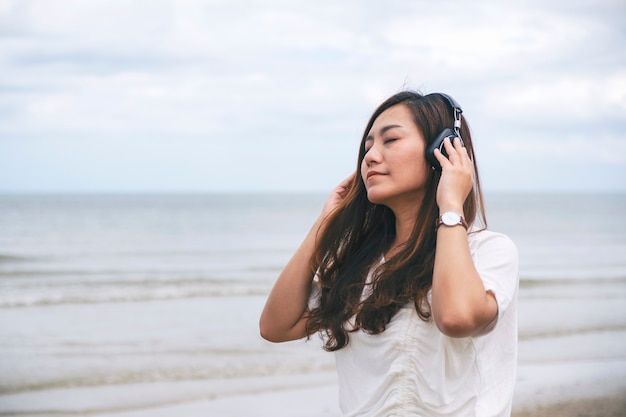 Una donna triste che ascolta musica con le cuffie in riva al mare