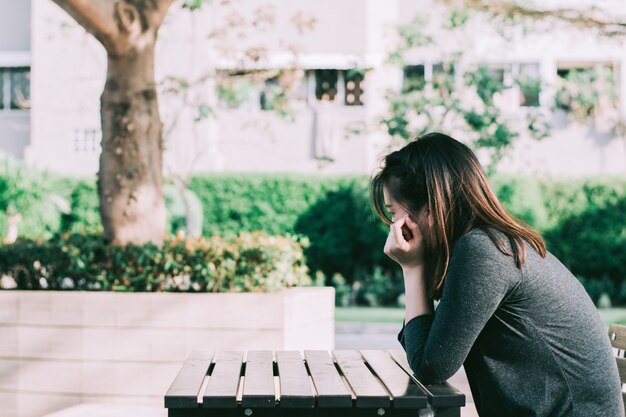 Una donna triste, sconvolta e preoccupata che si siede da solo all&#39;aperto