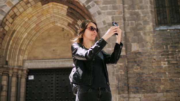 Una donna turistica attraente che fa un selfie usa uno smartfone mentre cammina per strada