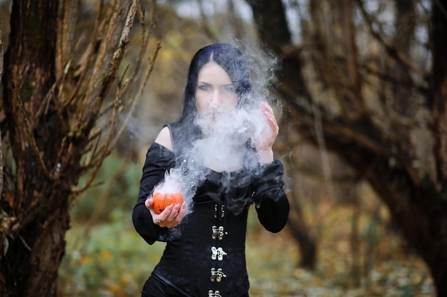 Una donna vestita da strega in una fitta foresta durante un rituale