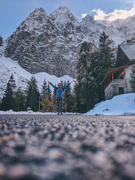 Una donna viaggiatrice si trova sulla strada e ammira la vista delle cime innevate delle Alpi