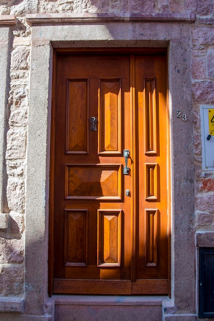 Una doppia porta in legno con finestre marrone scuro con un muro di pietra