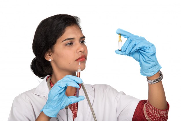Una dottoressa con uno stetoscopio tiene un'iniezione o una siringa.