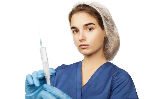 Una dottoressa in guanti blu e un camice chirurgico tiene una siringa con un farmaco nelle sue mani davanti al suo concetto di salute Anestesia o vaccino per virus e malattie Cure mediche ospedaliere
