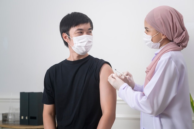 Una dottoressa musulmana che inietta il vaccino covid-19 al braccio del paziente, la vaccinazione covid-19 e il concetto di assistenza sanitaria