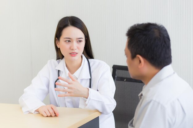 Una dottoressa professionista asiatica suggerisce una soluzione sanitaria al suo paziente anziano