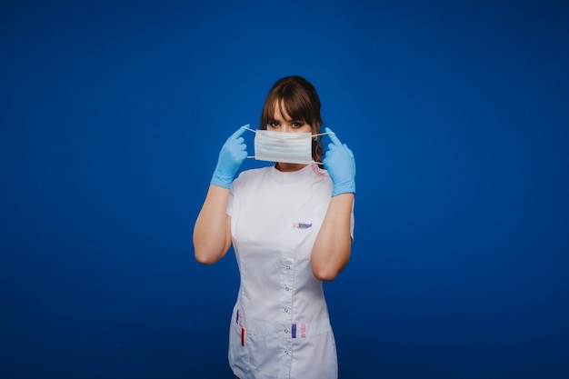 Una dottoressa si trova in una maschera medica, isolata su uno sfondo grigio.