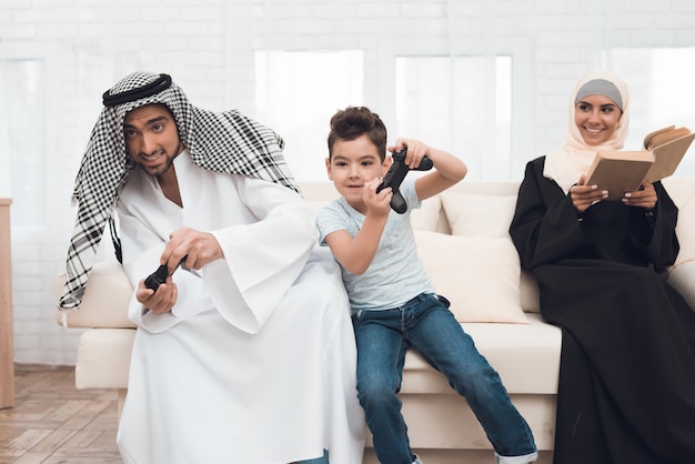 Una famiglia araba tradizionale gioca su una console di gioco.