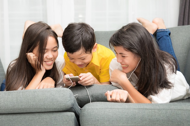 Una famiglia asiatica di tre bambini, un ragazzo e due ragazze, stanno giocando insieme con la felicità in casa