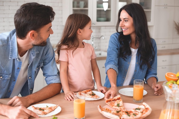 Una famiglia caucasica di tre persone che mangia pizza per cena insieme