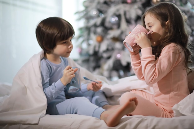 Una famiglia con bambini che si diverte sul letto sotto le coperte durante le vacanze di Natale