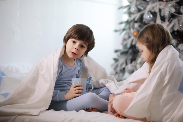 Una famiglia con bambini che si diverte sul letto sotto le coperte durante le vacanze di Natale