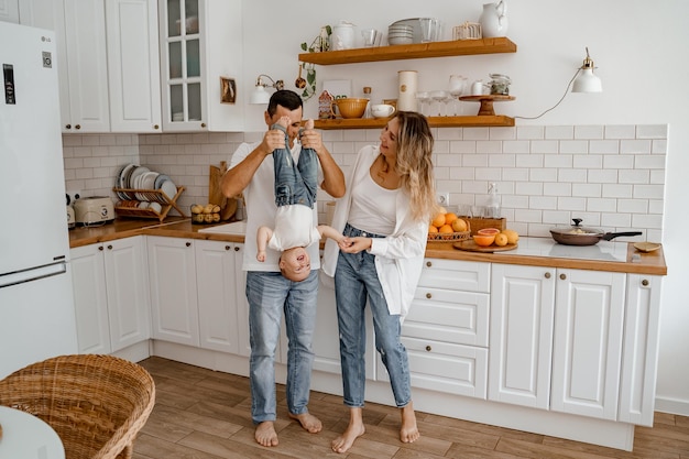 una famiglia con un bambino in jeans e magliette bianche sta giocando in cucina