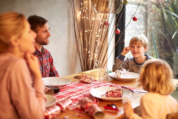 Una famiglia di quattro persone a un pasto di Natale tirando cracker