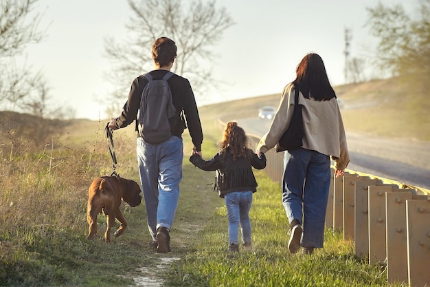 una famiglia di tre viaggiatori e un cane cammina lungo una strada polverosa