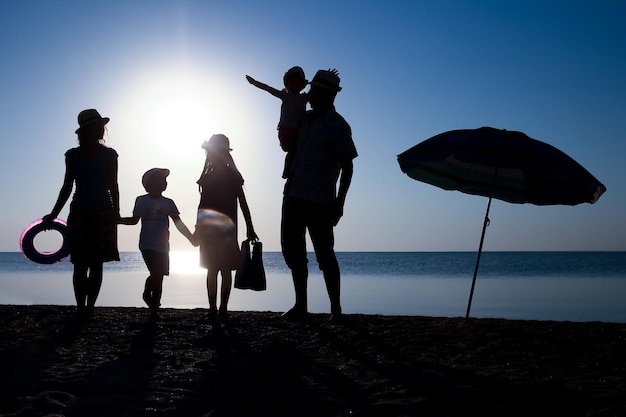 Una famiglia felice al mare al tramonto in silhouette di viaggio in natura