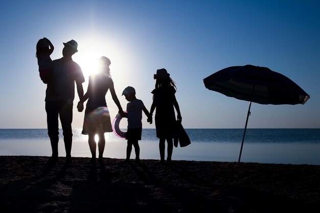 Una famiglia felice al mare al tramonto in silhouette di viaggio in natura