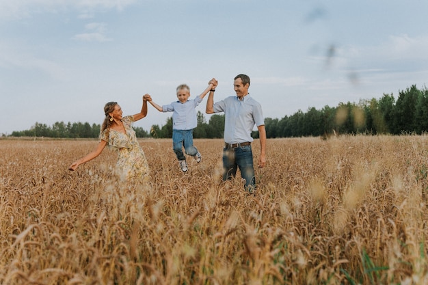 una famiglia felice cammina in un campo di grano divertendosi e ridendo