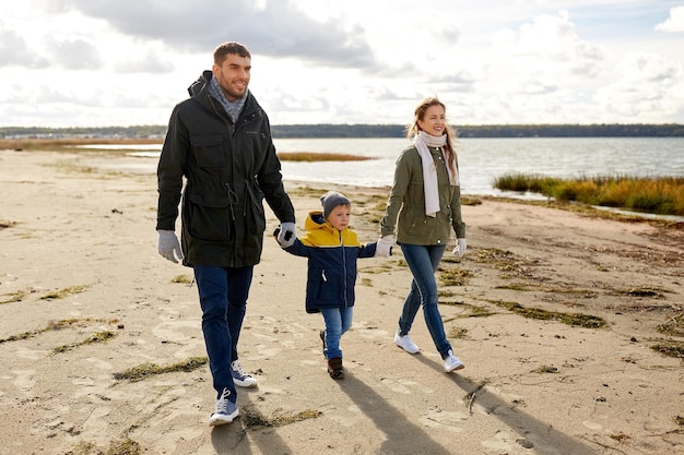 una famiglia felice che cammina lungo la spiaggia d'autunno