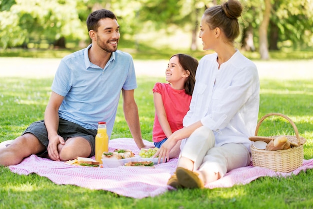 una famiglia felice che fa un picnic al parco estivo
