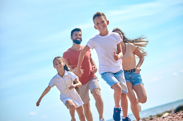 Una famiglia felice che si sente eccitata e corre su una spiaggia