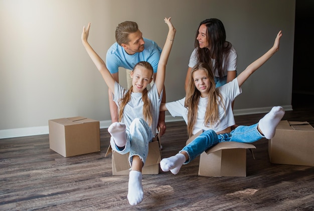 Una famiglia felice con due figlie si diverte nella loro nuova casa Genitori con bambini si godono la loro giornata in movimento