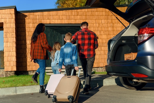Una famiglia felice decomprime i bagagli dal bagagliaio di un'auto dopo essersi trasferiti in una nuova casa.