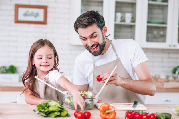 Una famiglia felice di due persone che preparano insieme l'insalata sulla cucina