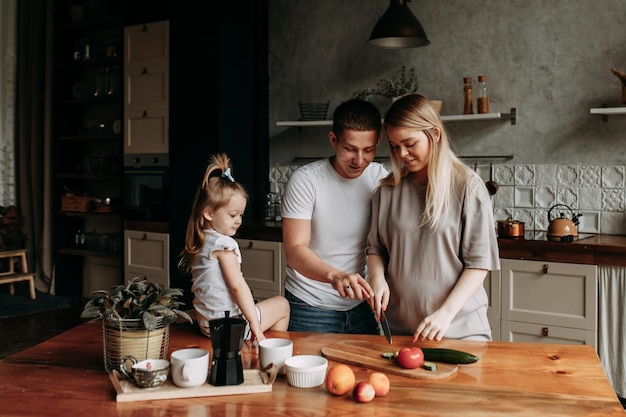 Una famiglia felice e allegra con un bambino sta cucinando insieme in cucina a casa