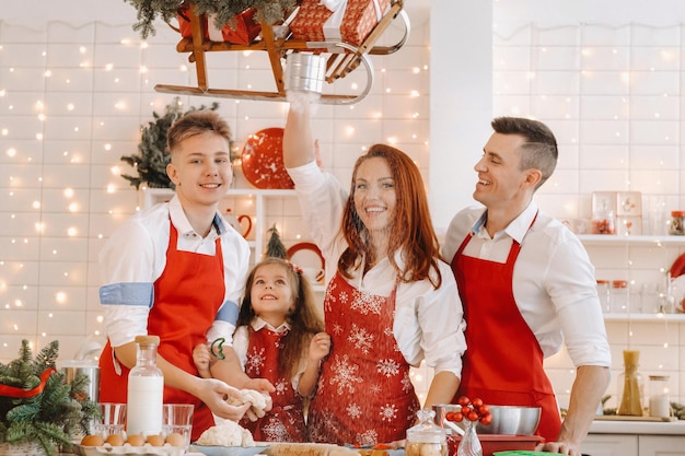 Una famiglia felice è in piedi nella cucina di Natale e prepara l'impasto per fare i biscotti