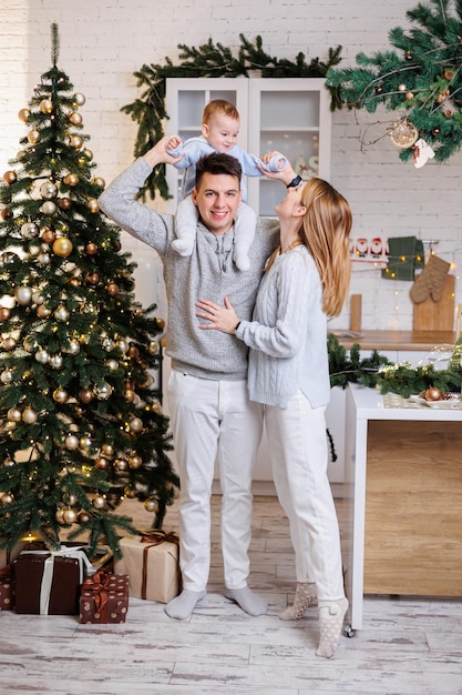 Una famiglia felice Felice giovane coppia con il figlio piccolo in cucina decorato per il nuovo anno Interni di Capodanno in cucina Cucina natalizia Atmosfera familiare festosa