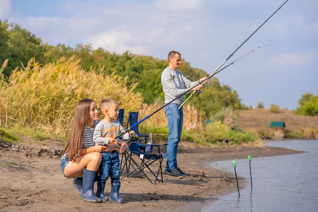 Una famiglia felice trascorre del tempo insieme; insegnano al figlio a pescare.
