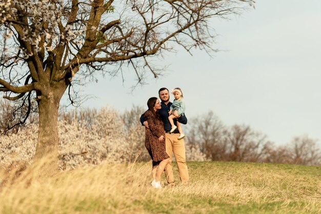 Una famiglia giovane e felice cammina nella natura con la figlia incinta durante una passeggiata con la sua passeggiata primaverile in famiglia