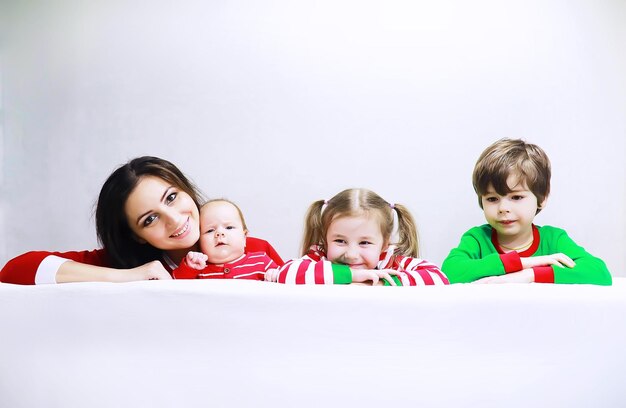 Una famiglia in pigiama a righe riposa a casa Bambini piccoli vestiti da elfi sdraiati sul divano Famiglia felice con banner