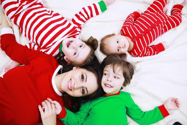 Una famiglia in pigiama a righe riposa a casa. I bambini vestiti da elfi sono sdraiati sul divano. Una famiglia felice.