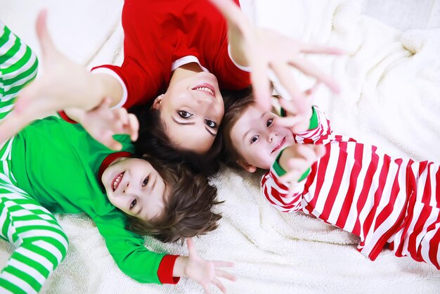 Una famiglia in pigiama a righe riposa a casa. I bambini vestiti da elfi sono sdraiati sul divano. Una famiglia felice.